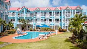 Un hôtel doté d’une piscine, de chaises longues et d’une pelouse bien entretenue.