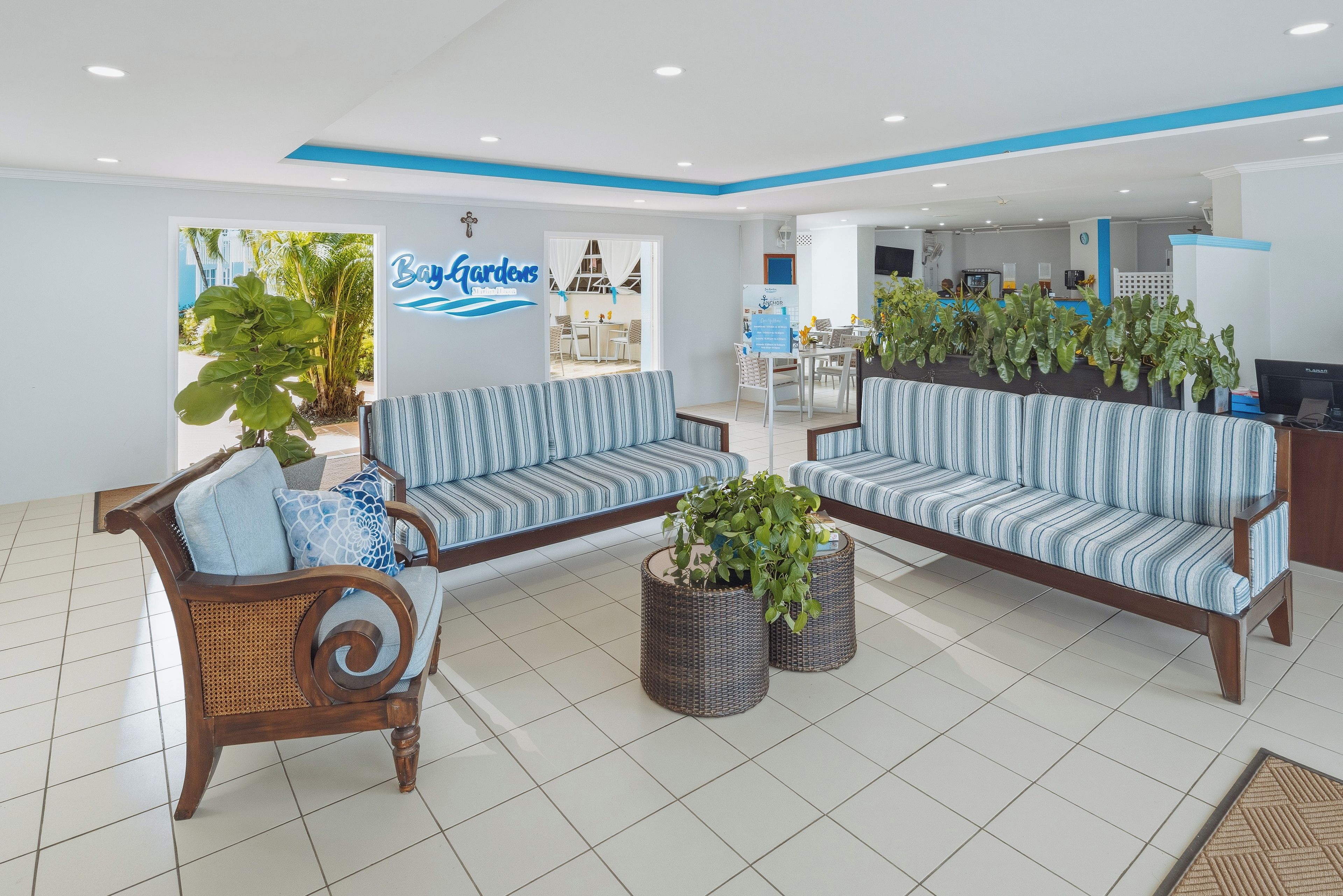 A hotel lobby with striped sofas, a reception desk, and potted plants.