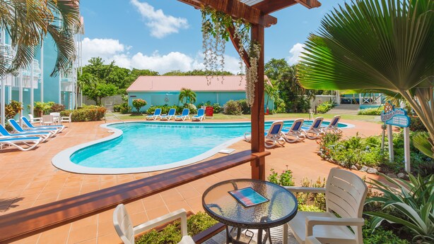 Un espace piscine avec des chaises longues, un coin salon abrité et un bâtiment en arrière-plan.