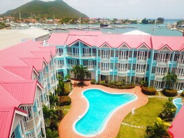 Een resort met een zwembad, meerdere balkons en een jachthaven op de achtergrond.