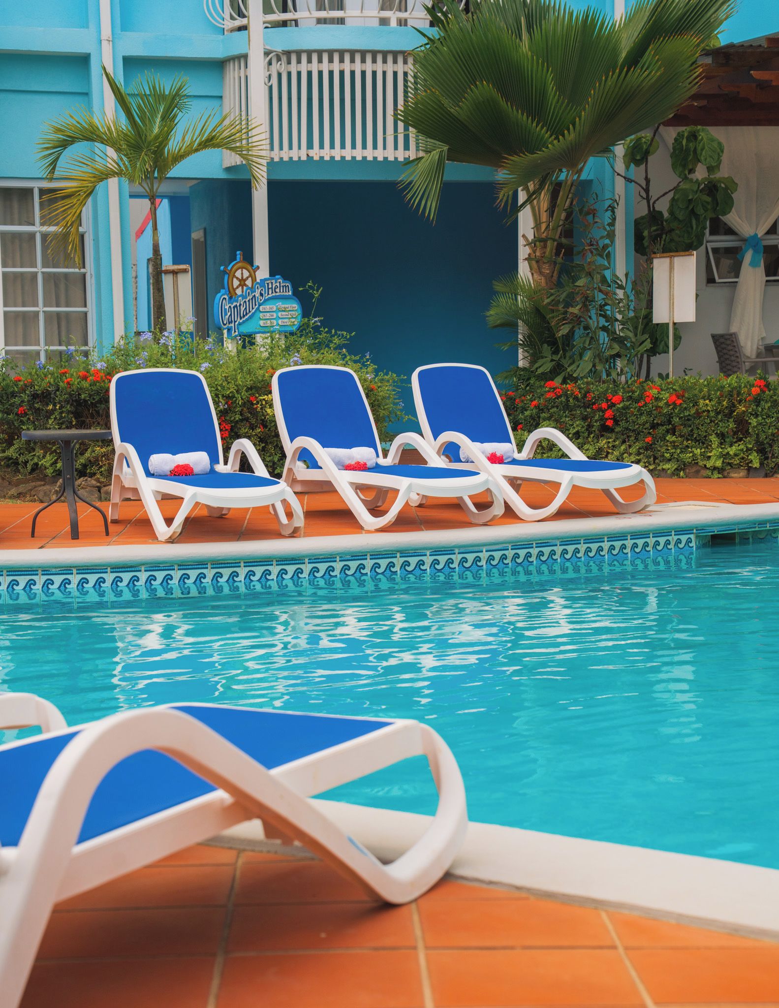 A poolside area with lounge chairs and a sign for 'Captain's Helm'.