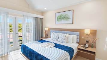 Une chambre d’hôtel avec un grand lit, une vue sur l’extérieur grâce à une porte coulissante, une plante décorative accrochée au mur et une table de chevet avec un téléphone et un vase.