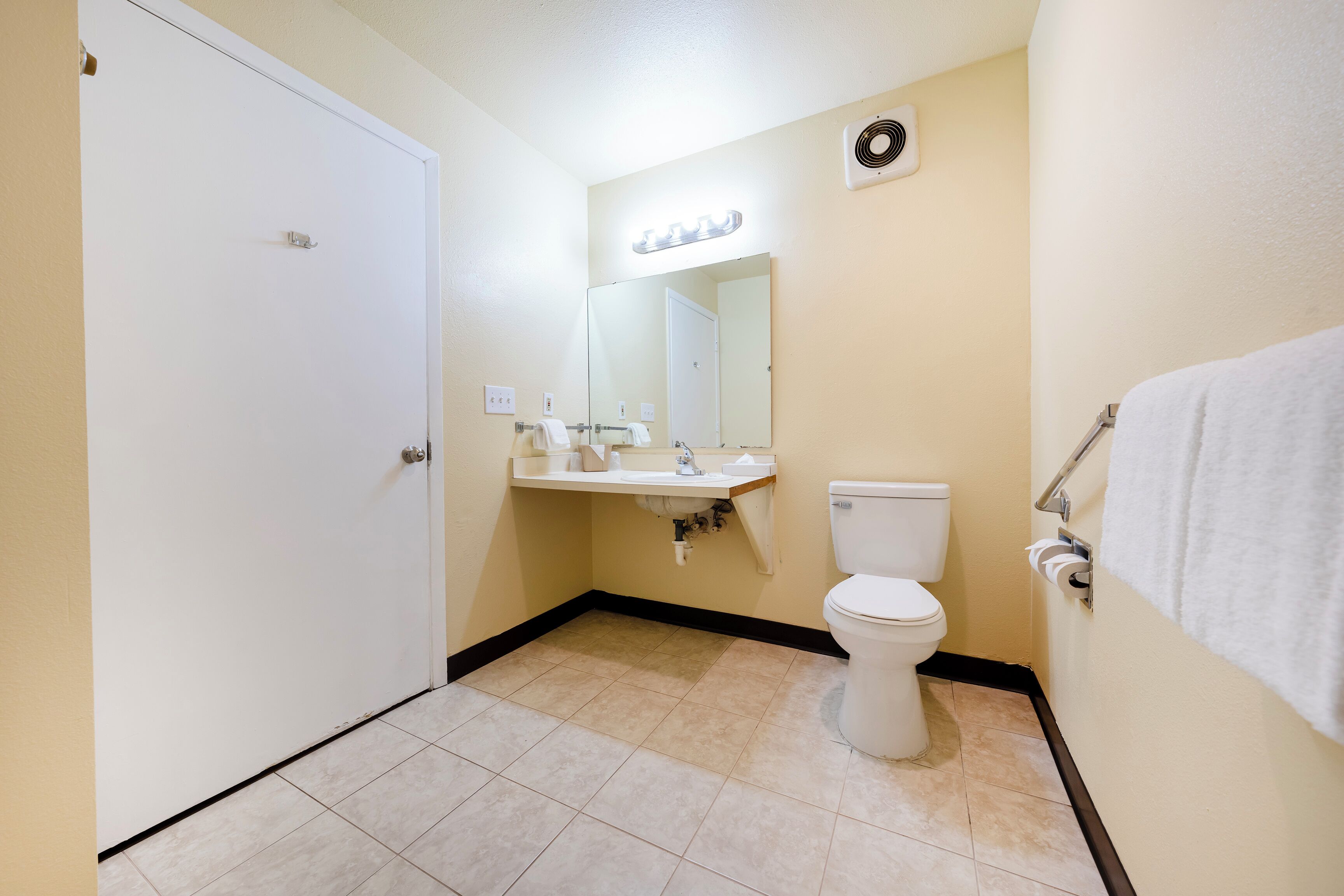 Une salle de bain équipée de toilettes, d’un lavabo, d’un miroir et d’un porte-serviettes.