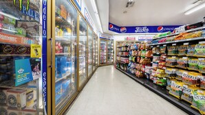 A grocery store aisle with refrigerated sections on the left and snack shelves on the right. - King City Motel by OYO Pasco (Pasco)