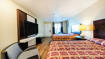 A hotel room with two beds, a TV, a desk, and a lamp.