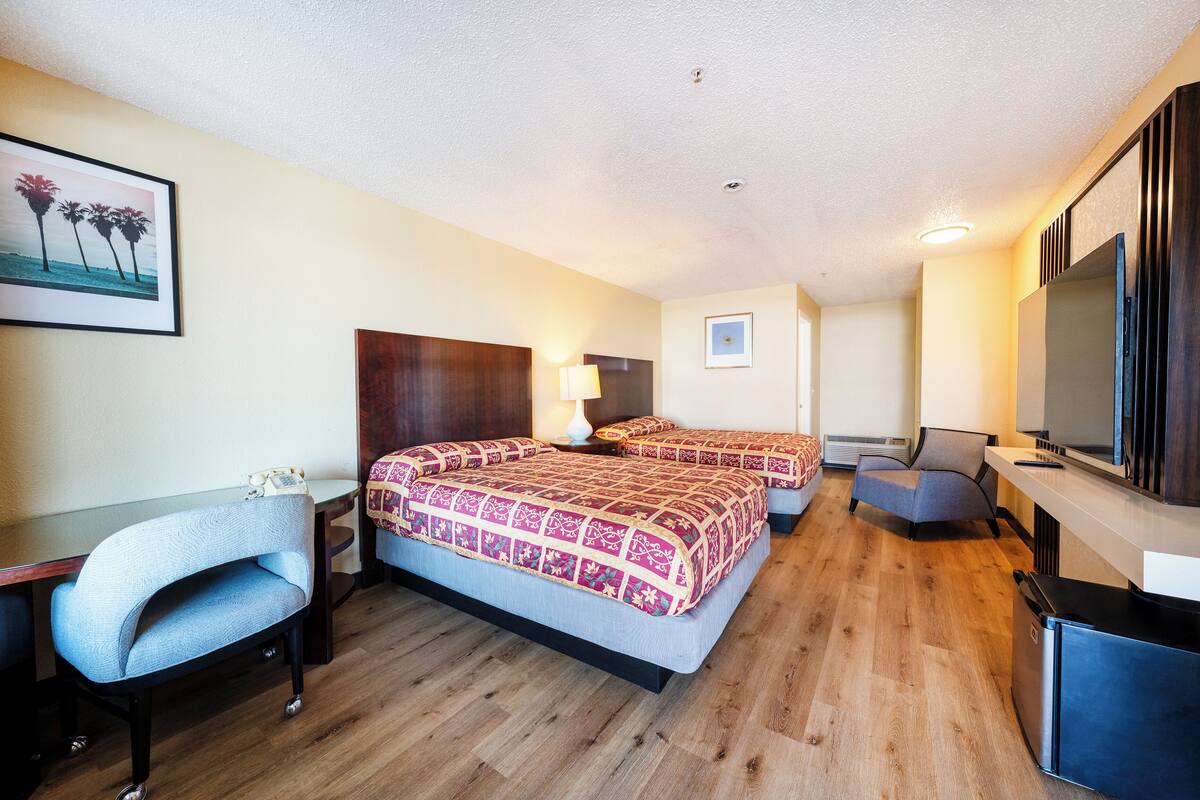 A hotel room with a bed, a desk, a chair, a TV, and a picture on the wall.