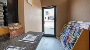 A hotel reception area with a counter, a QR code, a framed welcome sign, and a display of brochures. - King City Motel by OYO Pasco (Pasco)
