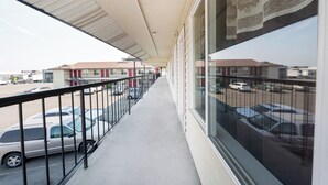 A covered balcony with a view of parked cars and buildings in the background. - King City Motel by OYO Pasco (Pasco)