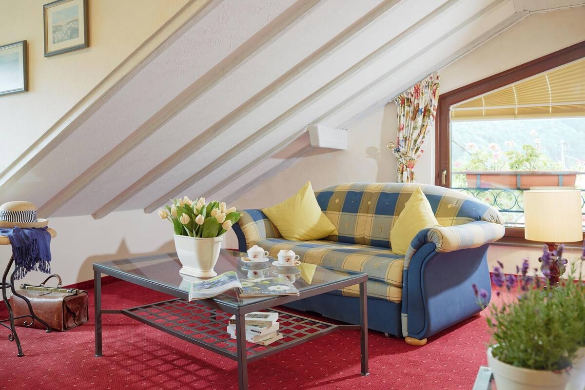 A cozy living room with a blue and yellow sofa, a glass coffee table, and a red carpet.