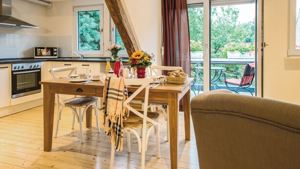 Una cucina moderna con zona pranzo, pavimento in legno e vista sull'esterno.