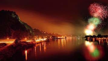 A nighttime view of a river with reflections of lights, a bridge, and a hill in the background.