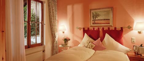 Une chambre à coucher avec un lit, une fenêtre avec des rideaux, une table de chevet avec une lampe et un tableau accroché au mur.