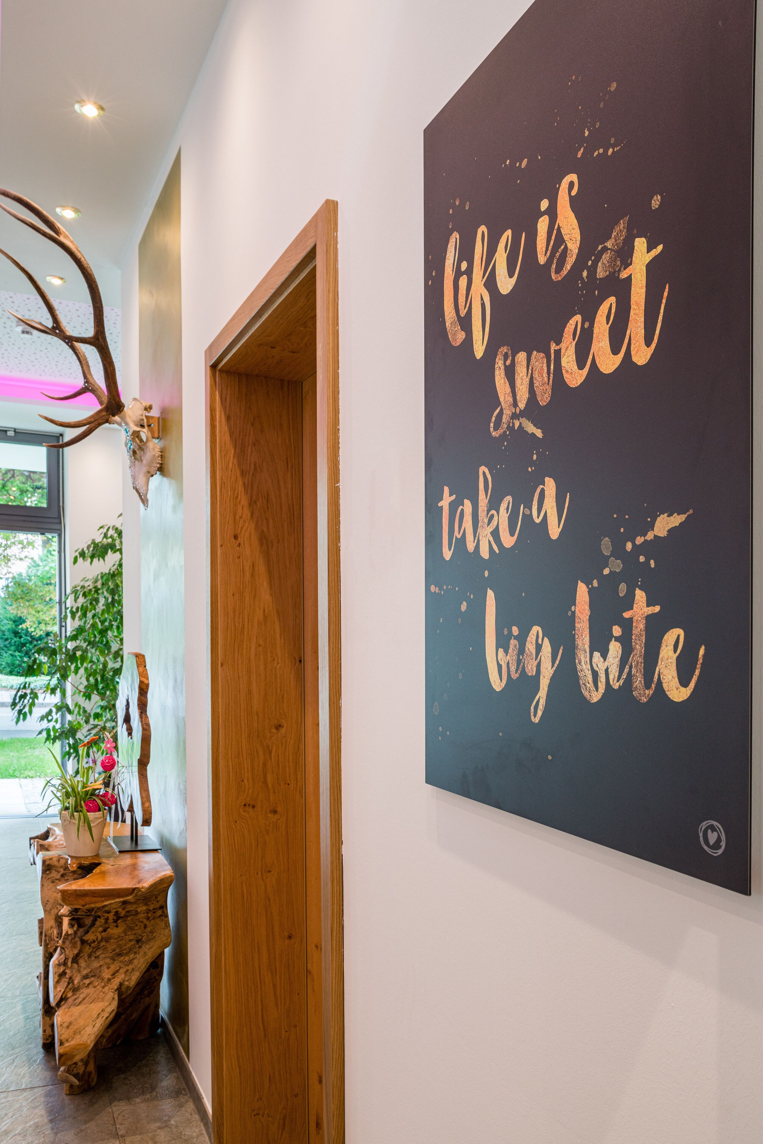A hallway with a large motivational poster, a wooden door, and a rustic wooden bench with a potted plant.