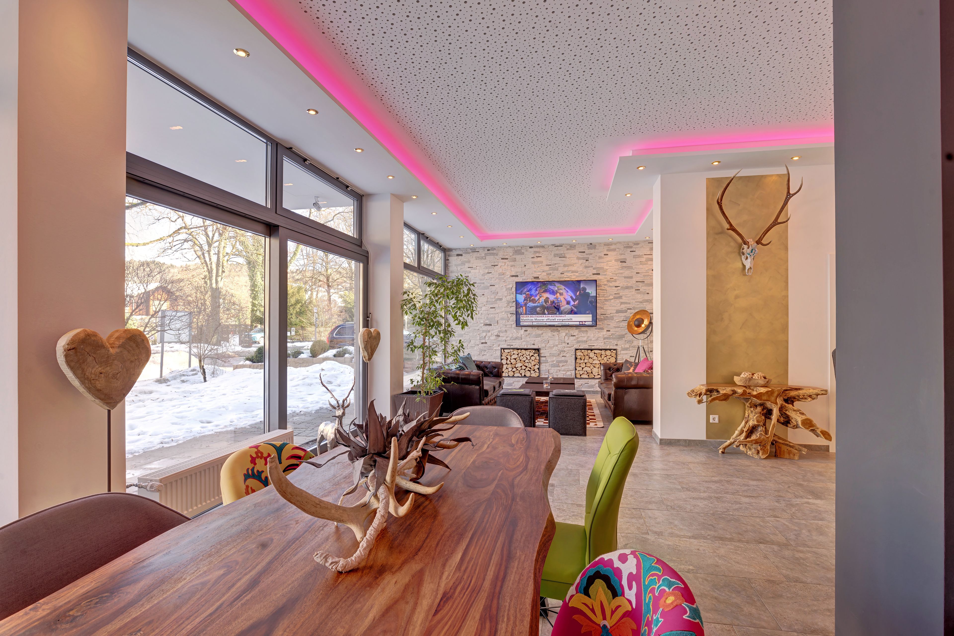 A modern dining area with a large wooden table, heart-shaped decor, and antler display.
