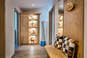 A wooden hallway with a bench and shelves displaying deer antlers and a welcome sign.