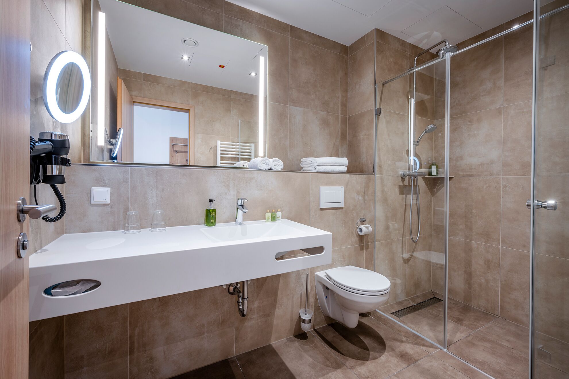 A modern bathroom with a glass shower enclosure, a white sink with a mirror, and a toilet.