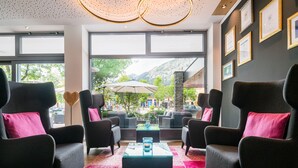 A modern lounge area with large windows, comfortable seating, and a view of a mountain landscape.
