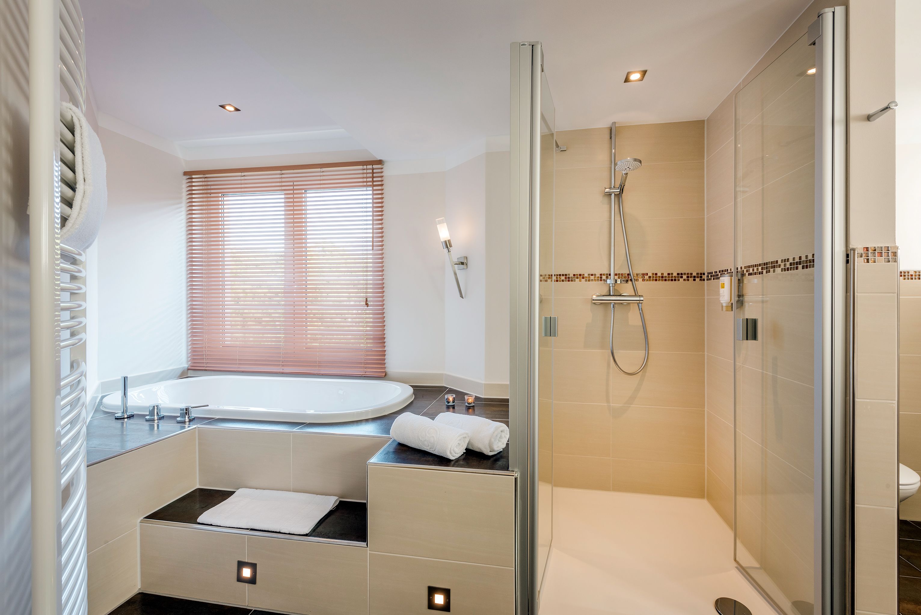 Une salle de bain moderne avec une douche à parois de verre, une grande baignoire et un meuble-lavabo avec un miroir.