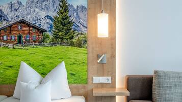 Una habitación de hotel con una cama, un sofá, una lámpara de pared y un mural de un paisaje montañoso.