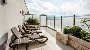 A terrace with lounge chairs, a table, and a view of the mountains.