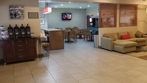 A spacious living area with a sofa, a coffee table, and a dining area with chairs and a table. There is a kitchen in the background, and a TV mounted on the wall. - Country Inn & Suites by Radisson, Canton, GA (Canton)