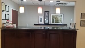 A hotel reception desk with framed certificates, a welcome sign, and a check-in/out time sign. - Country Inn & Suites by Radisson, Canton, GA (Canton)