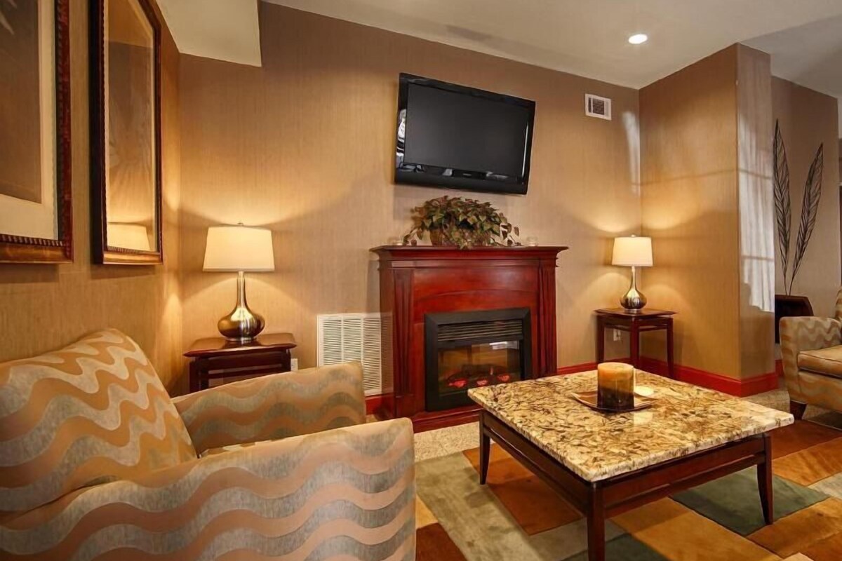 A living room with a fireplace, a television mounted on the wall, and two lamps on side tables.