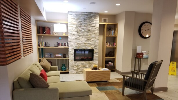A modern living room with a sectional sofa, a coffee table, a fireplace, and built-in bookshelves. - Country Inn & Suites by Radisson, Canton, GA (Canton)