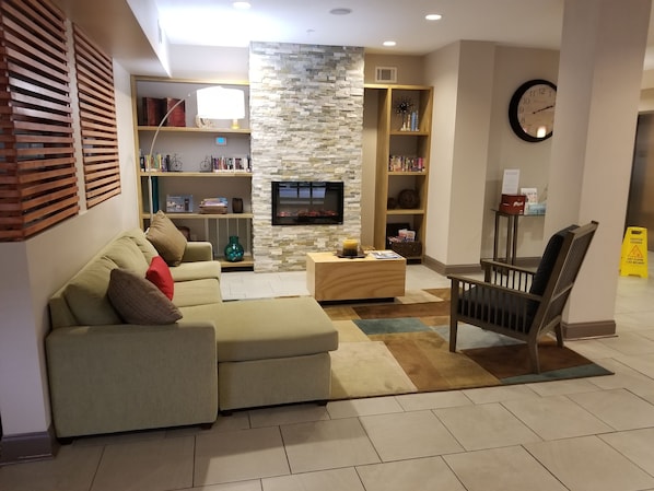 A modern living room with a sectional sofa, a coffee table, a fireplace, and built-in bookshelves. - Country Inn & Suites by Radisson, Canton, GA (Canton)