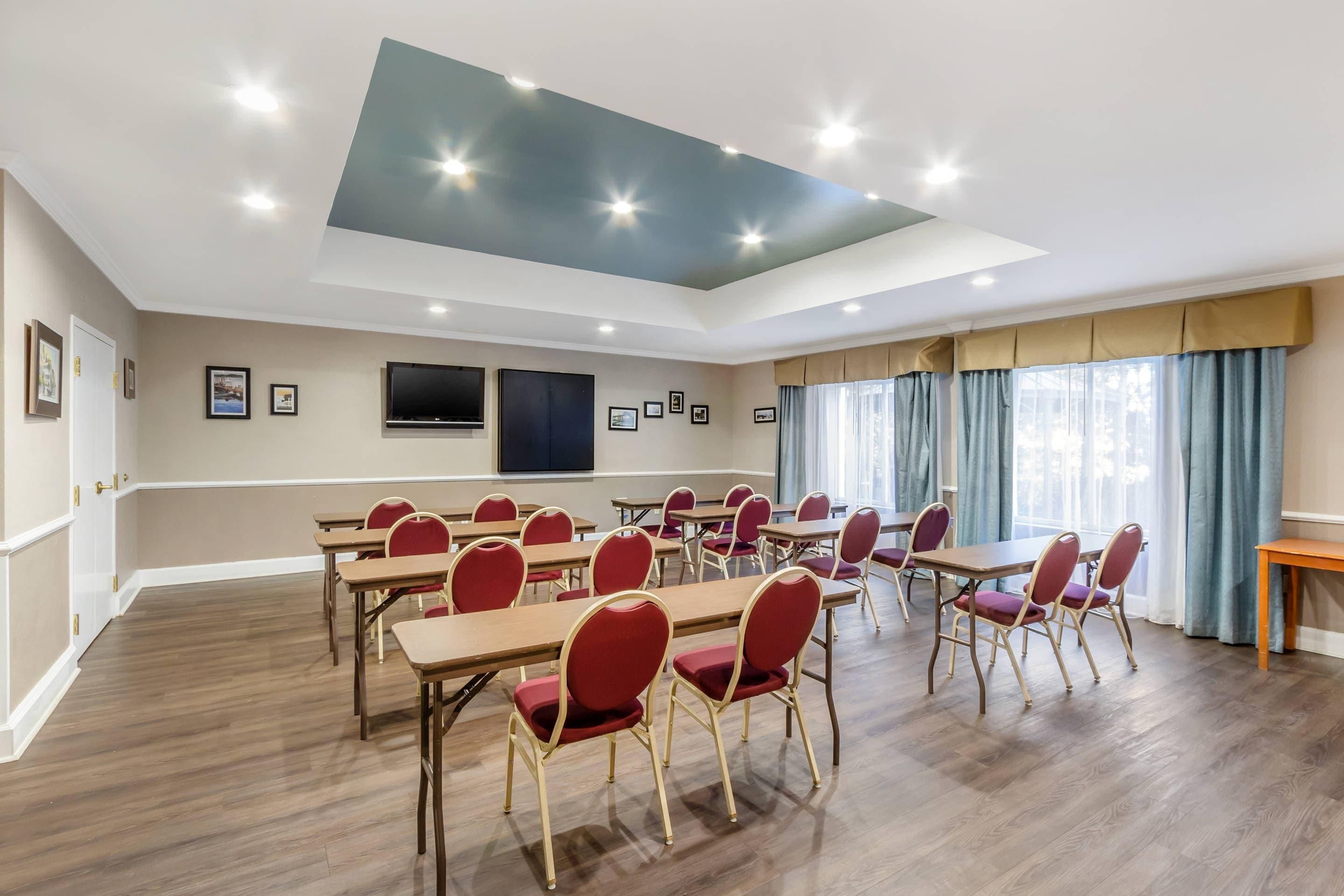 Una sala conferenze con tavoli e sedie, un televisore a schermo piatto e un lampadario.