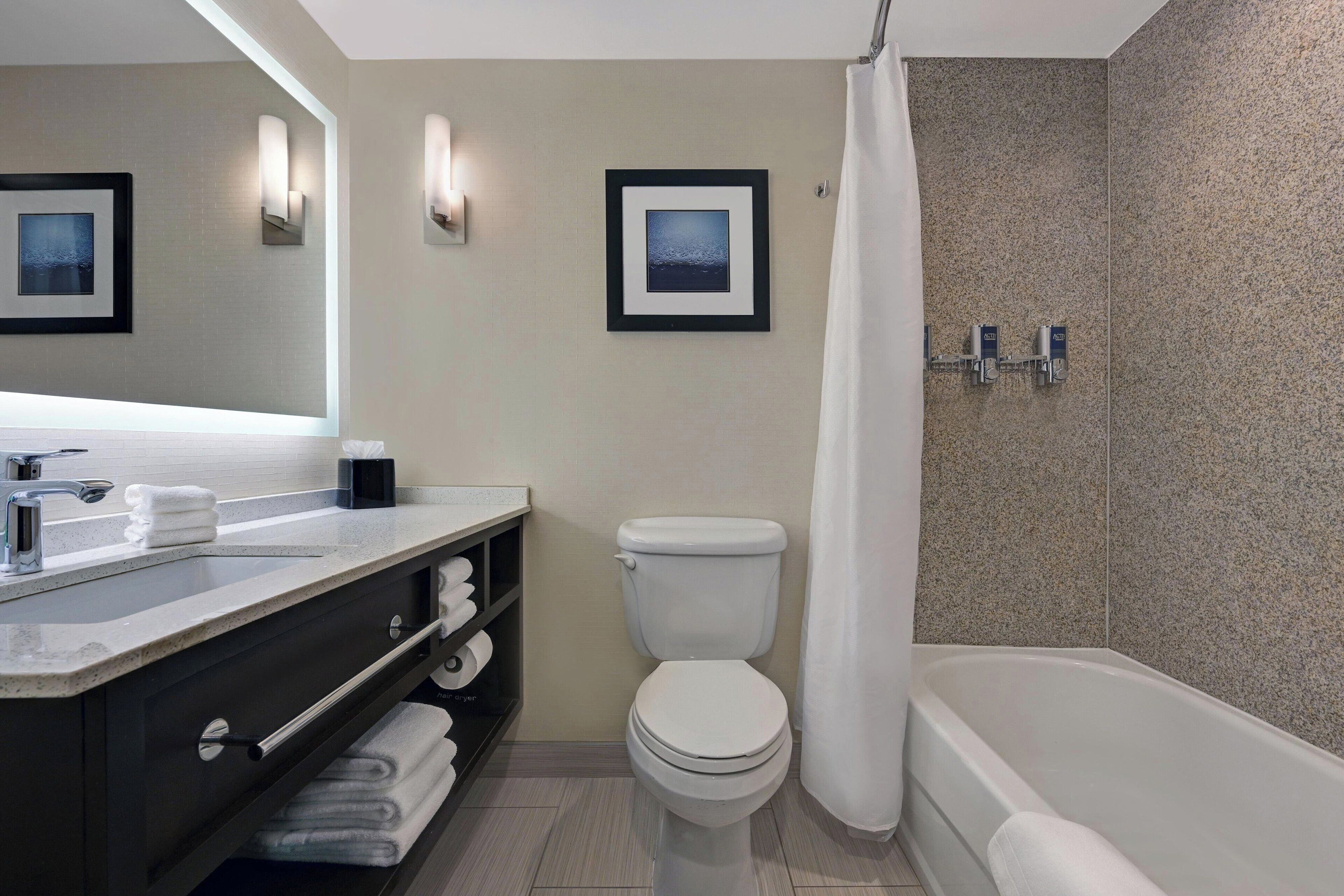A modern bathroom with a bathtub, toilet, and vanity.