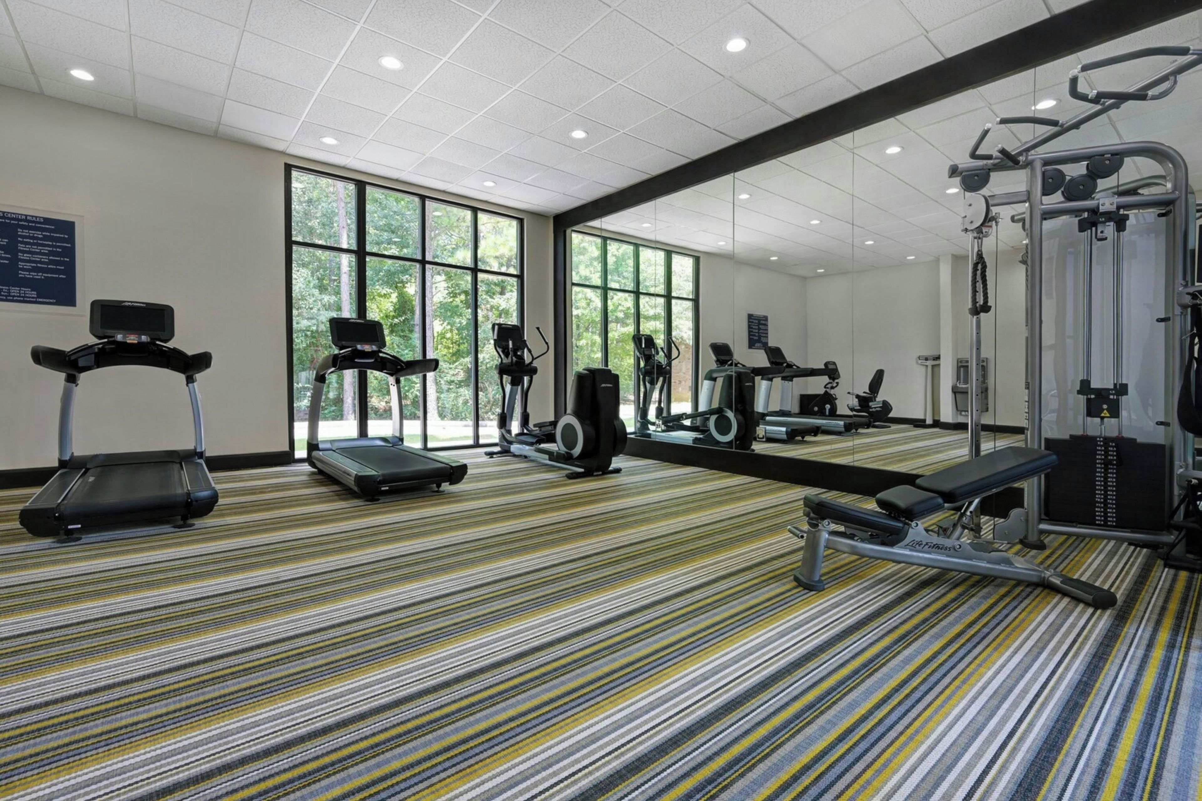 A gym with treadmills, elliptical machines, and weight equipment.