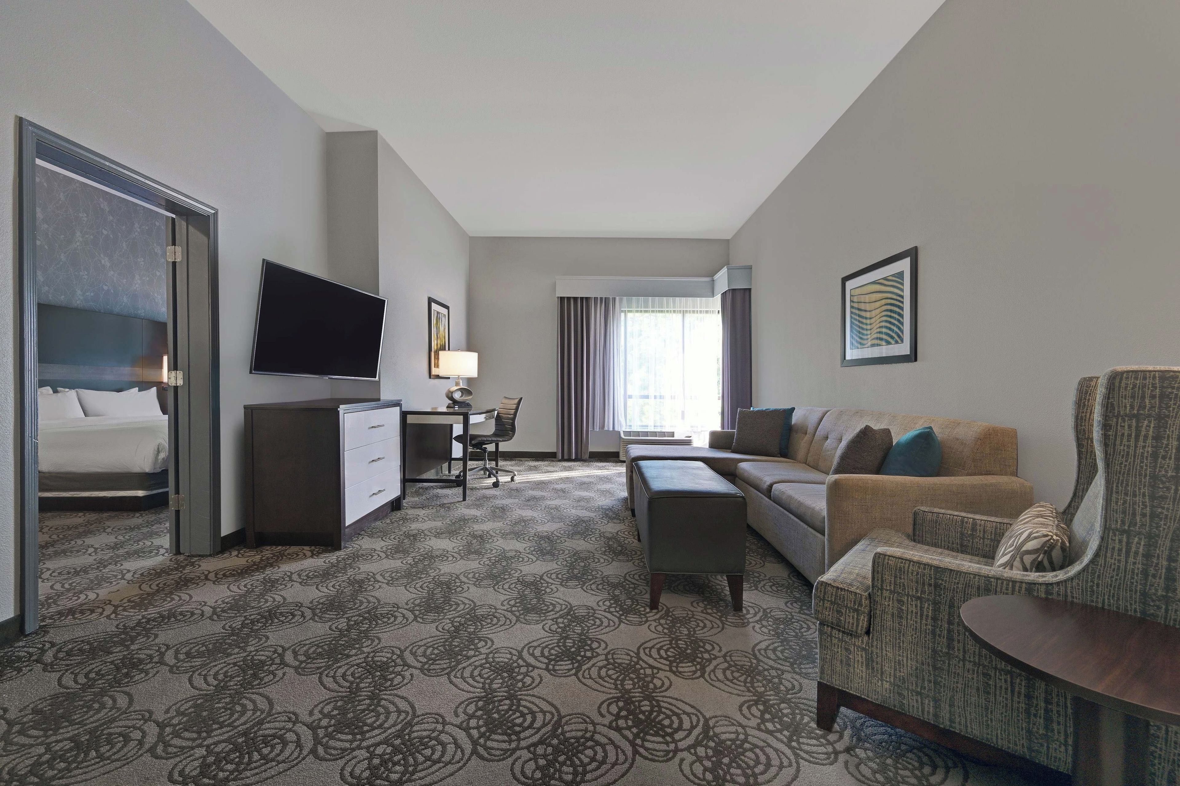 Ein Hotelzimmer mit Bett, Schreibtisch, Stuhl, Sofa und Fernseher.