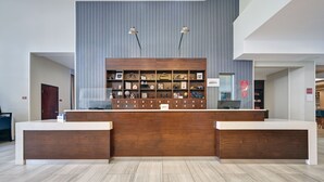 A reception desk with a wooden finish, two pendant lights, and a display of framed items above.