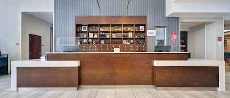 A reception desk with a wooden finish, two pendant lights, and a display of framed items above.