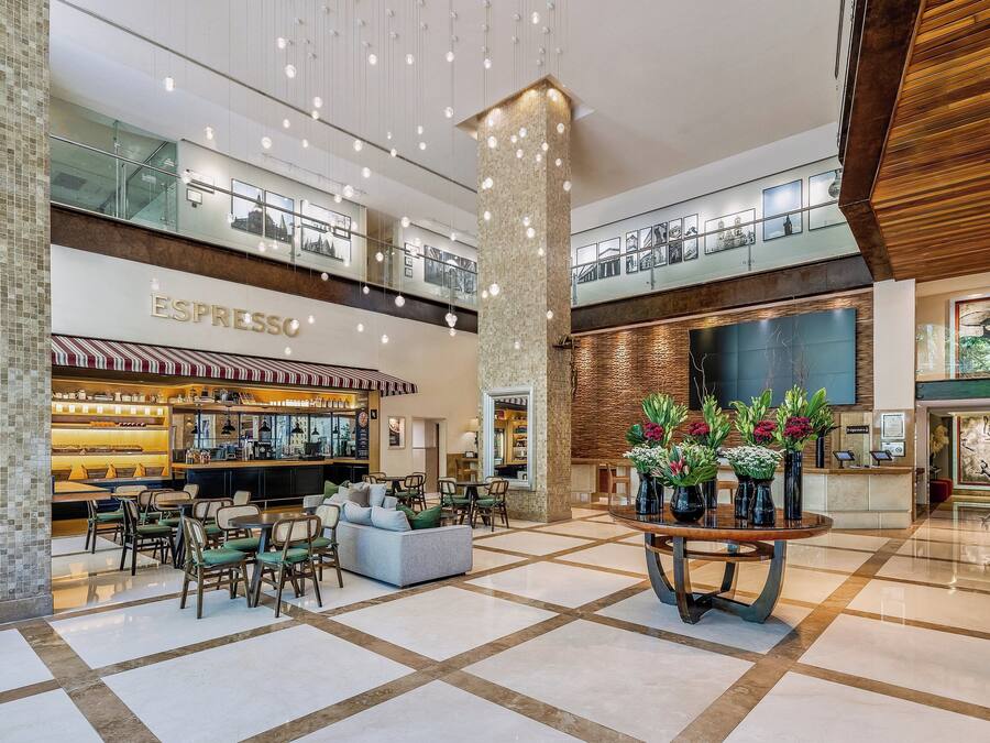 A spacious lobby with a coffee shop, seating area, and a reception desk.