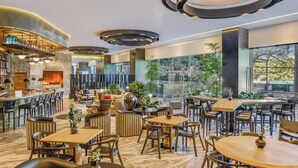 A modern hotel lobby with a bar, seating areas, and a fireplace.