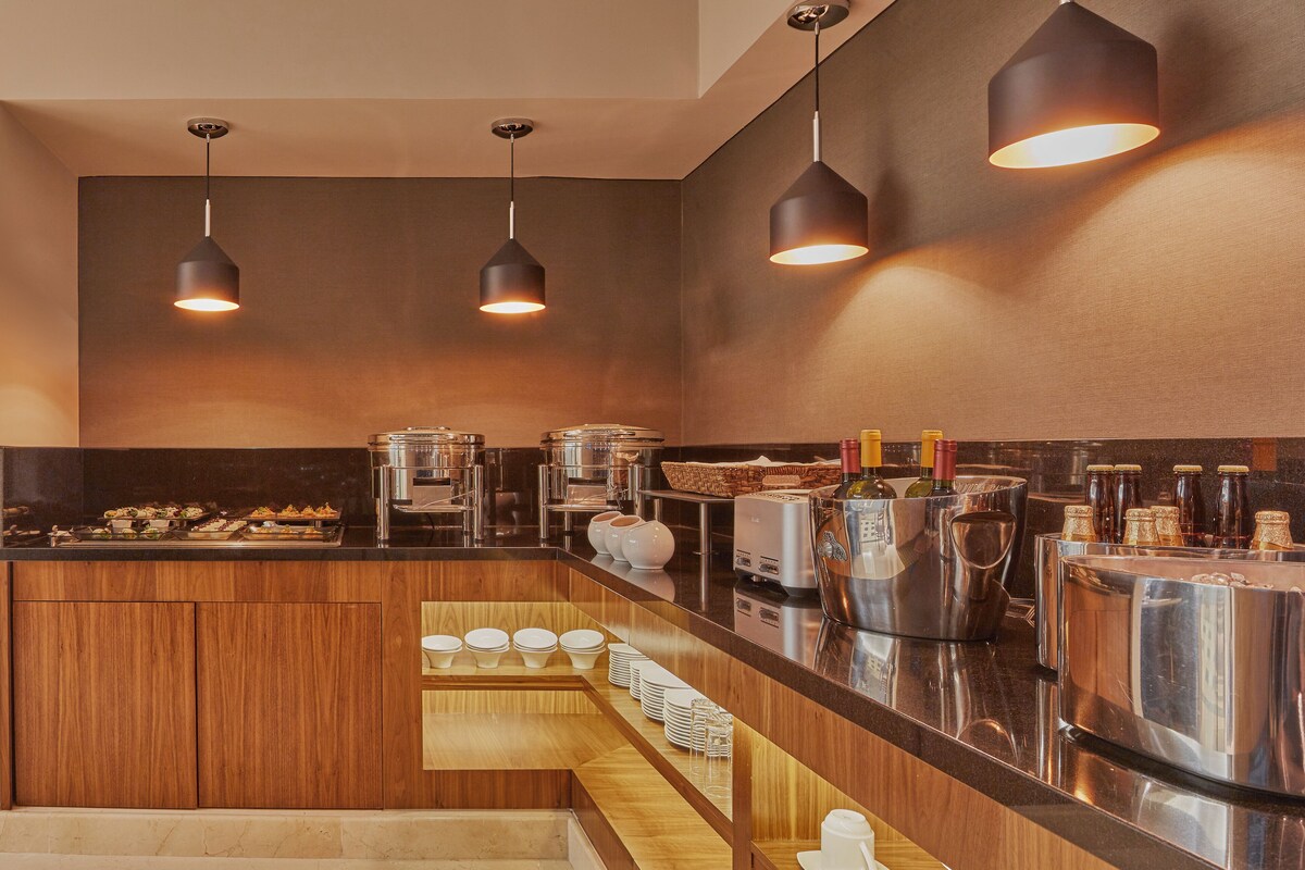 A modern kitchen with wooden cabinets, stainless steel appliances, and pendant lighting.