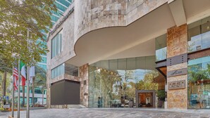 A modern hotel entrance with a curved overhang, glass facade, and a stone-textured exterior.