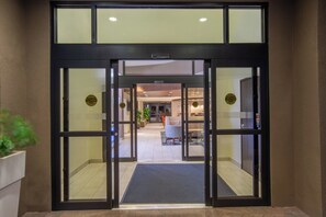 A hotel entrance with automatic caution doors, a reception area, and a seating area with tables and chairs. - Holiday Inn Express Surprise by IHG (Surprise)