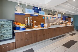 A modern breakfast area with labeled sections for fruit, cereal, hot food, and bakery.
