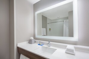 A modern bathroom with a large mirror, a white sink, and a towel rack.