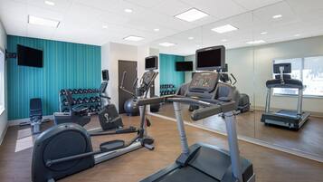 Een fitnessruimte met diverse trainingsapparaten, waaronder loopbanden, elliptische trainers en krachtapparaten.