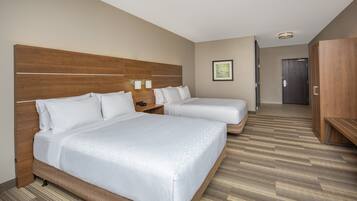 Habitación de hotel con dos camas, cabeceros de madera, un armario de madera y un cuadro enmarcado en la pared.