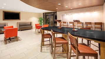 Une salle de conférence moderne, dotée d’une longue table, de chaises en bois et d’un grand écran.