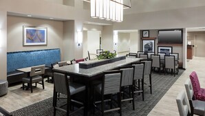 A modern hotel lobby with a bar area, seating, and a television. - Hampton Inn & Suites Davenport (Davenport)