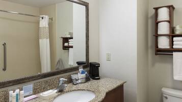 A bathroom with a granite countertop sink, a mirror, a towel rack, and a shelf with folded towels.