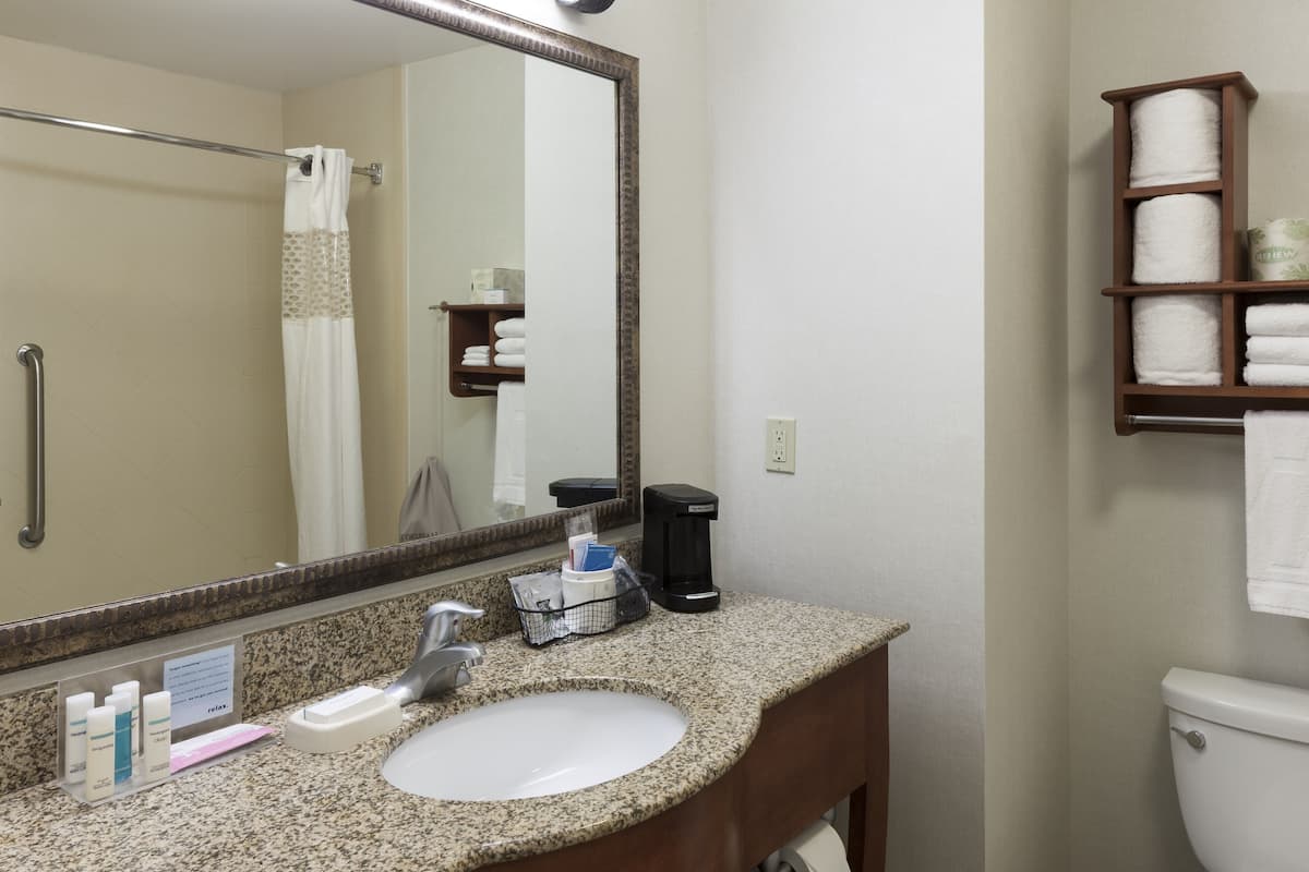 A bathroom with a sink, mirror, towel rack, and a toilet.
