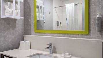 Un baño moderno con un lavabo blanco, un espejo de marco verde y un perchero con toallas dobladas.
