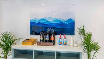 A bar area with a large painting of mountains, a coffee machine, and two bottles of coffee.
